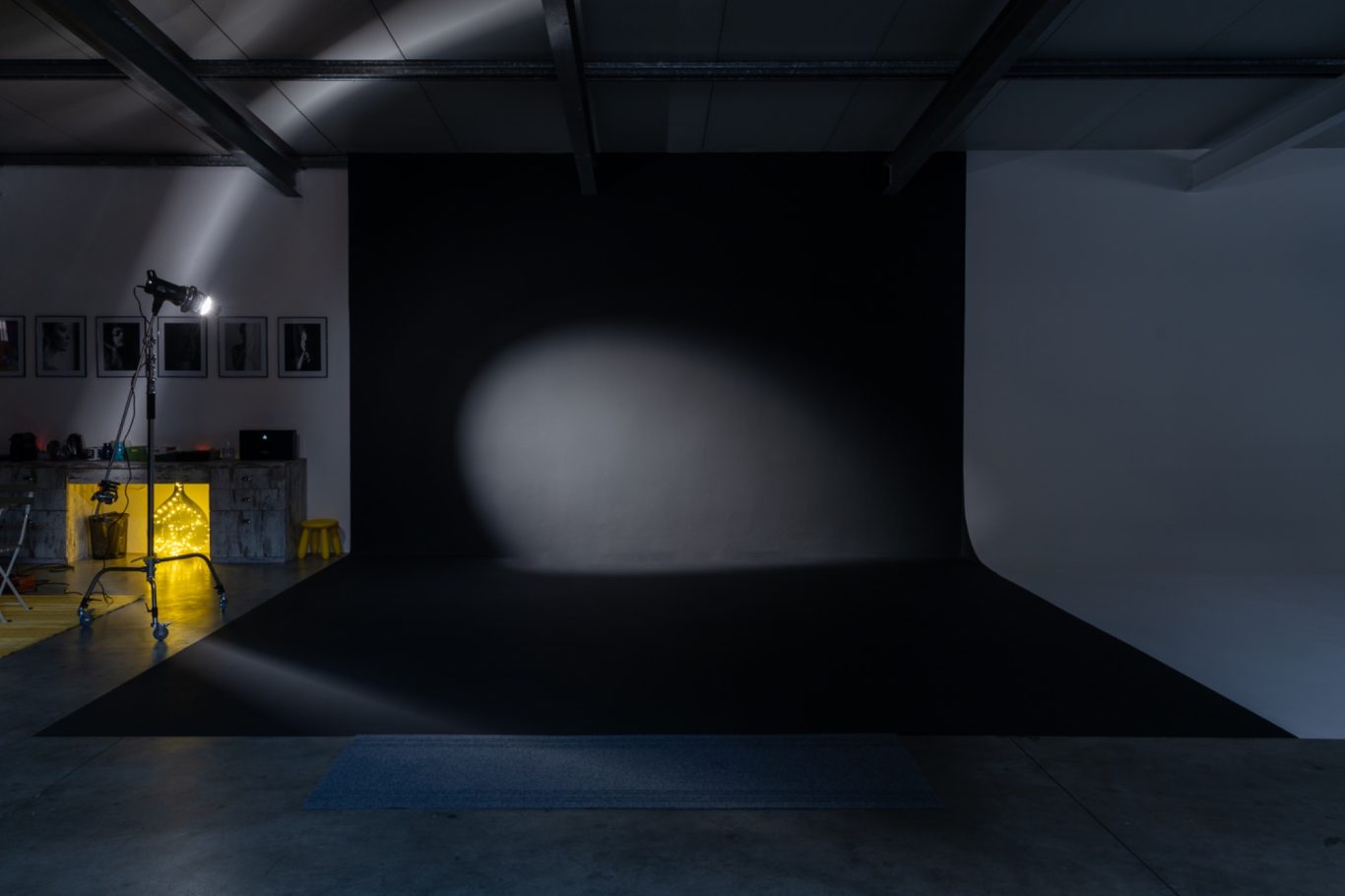 Studio fotografico con limbo nero, un riflettore e un tavolo con attrezzature.