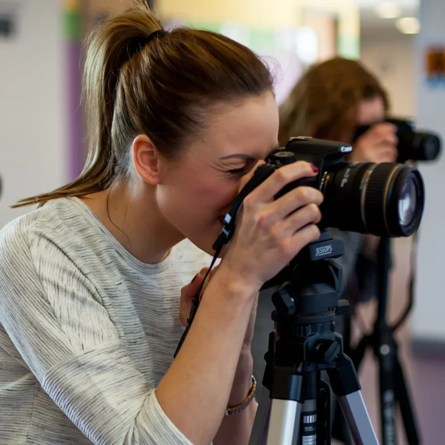 Una donna fotografa con una reflex mentre è in piedi su un treppiede.