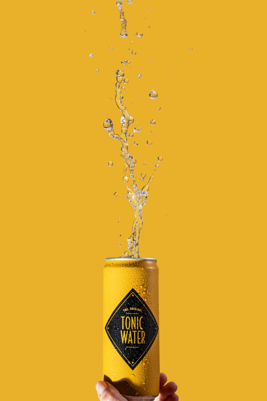 Lattina di soda gialla con liquido schizzi su uno sfondo giallo brillante. fotografia commerciale ad Alessandria