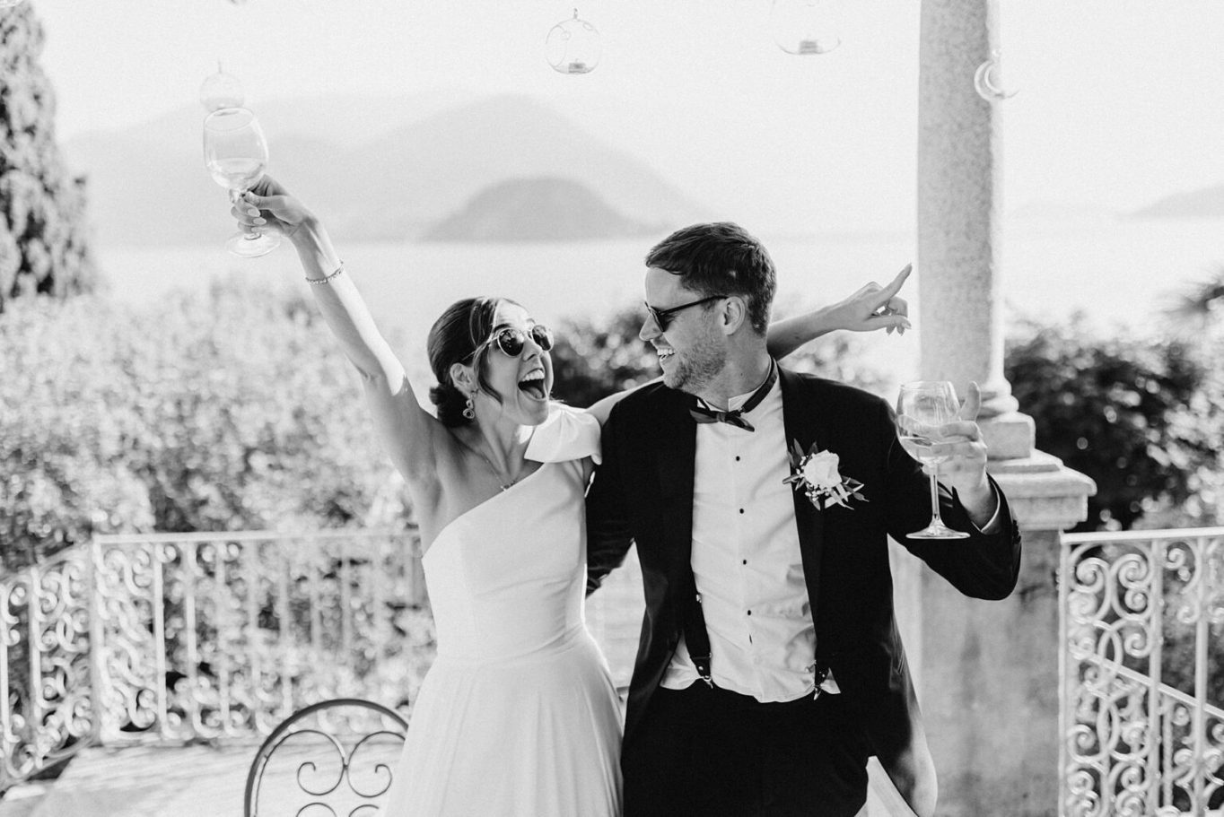 Sposi sorridenti brindano in un ambiente festoso con vista panoramica.