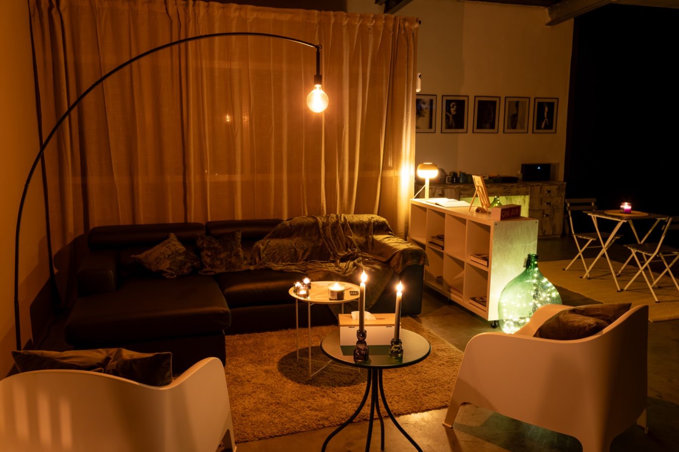 Salotto accogliente con divano, tavolino, candele accese e illuminazione soffusa.