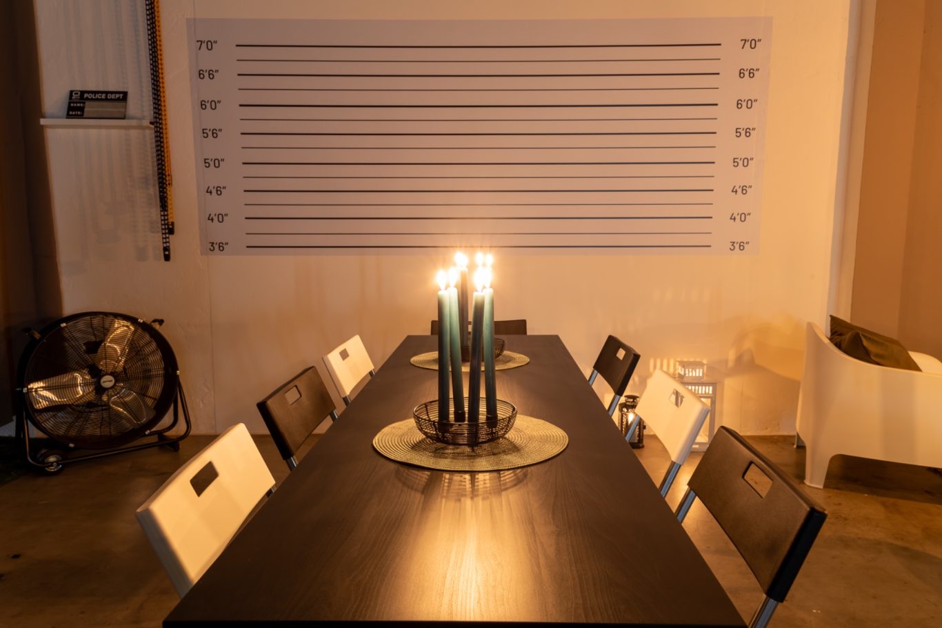 Tavolo lungo con candele accese e sedie disposte in un ambiente illuminato.