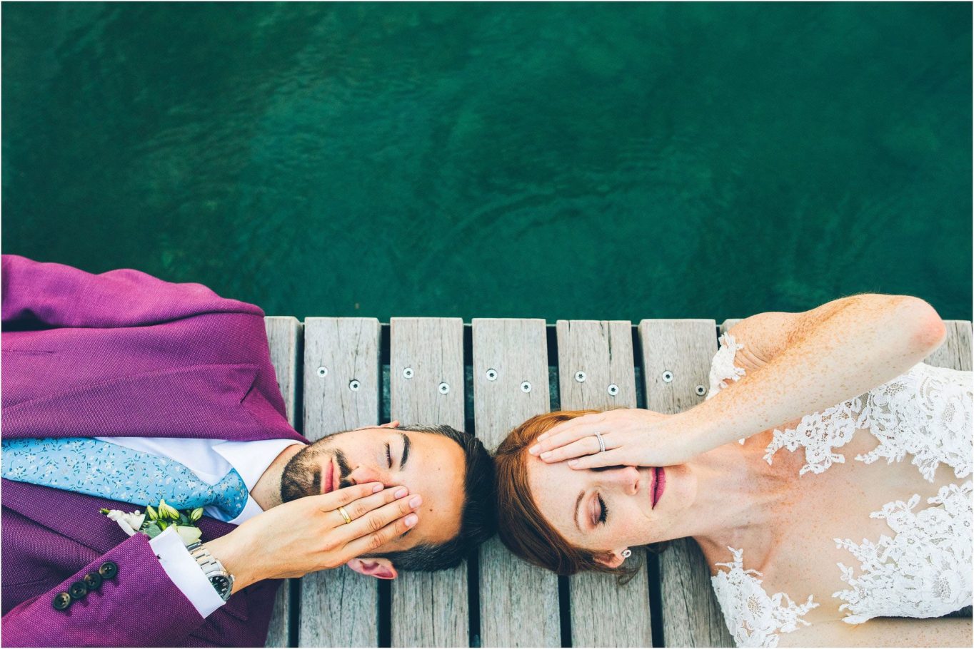 Sdraiati su un molo, una coppia di sposi  si copre scherzosamente il viso.