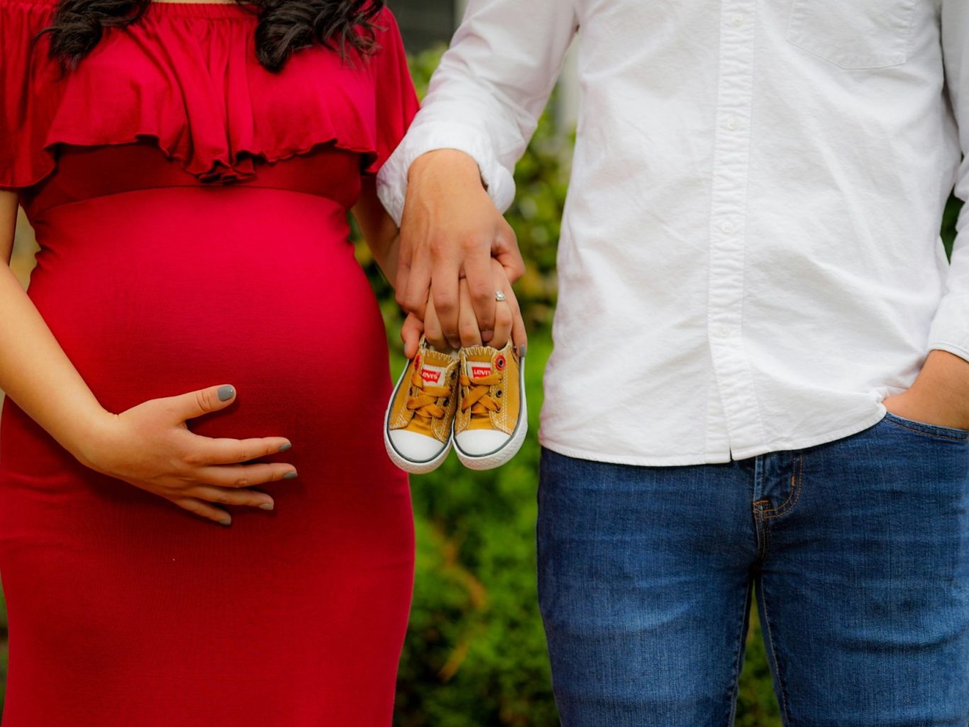 Una coppia tiene un paio di scarpine da neonato, la donna ha un pancione.
