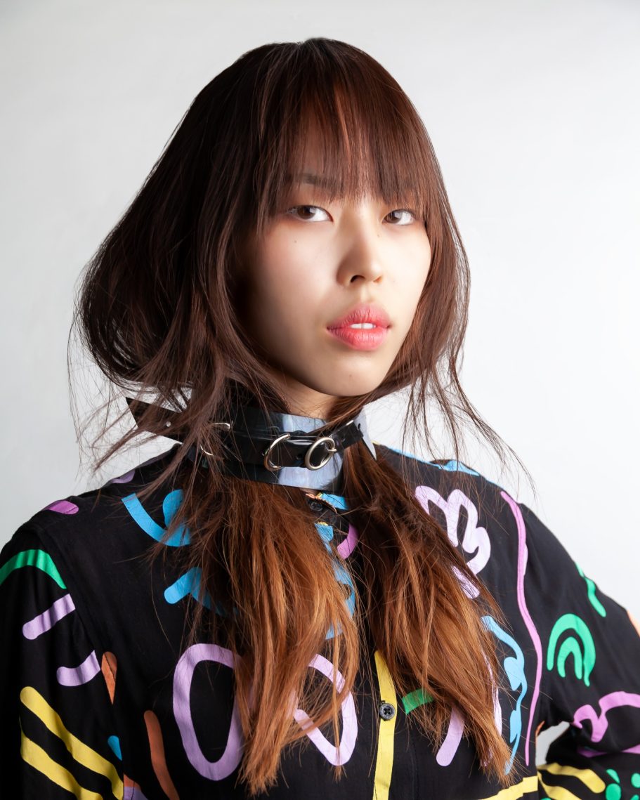 Giovane donna con lunghi capelli castani che indossa un maglione fantasia colorata.