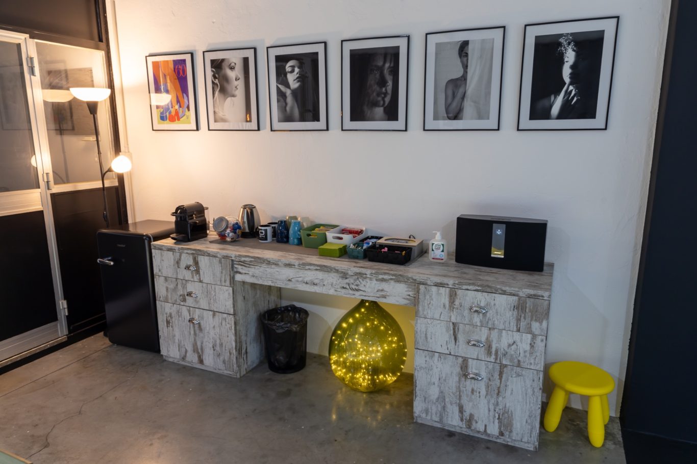 Interni moderni con un tavolo, oggetti decorativi e foto in bianco e nero incorniciate sul muro.