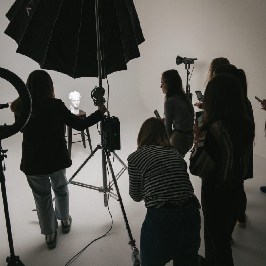 Gruppo di persone che allestiscono un servizio fotografico con apparecchiature di illuminazione in uno studio.